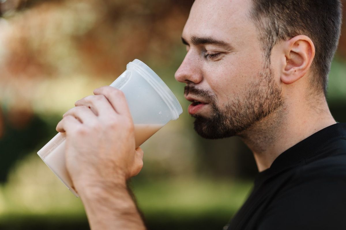 Homme barbu qui boit un smoothie dans un gobelet en extérieur