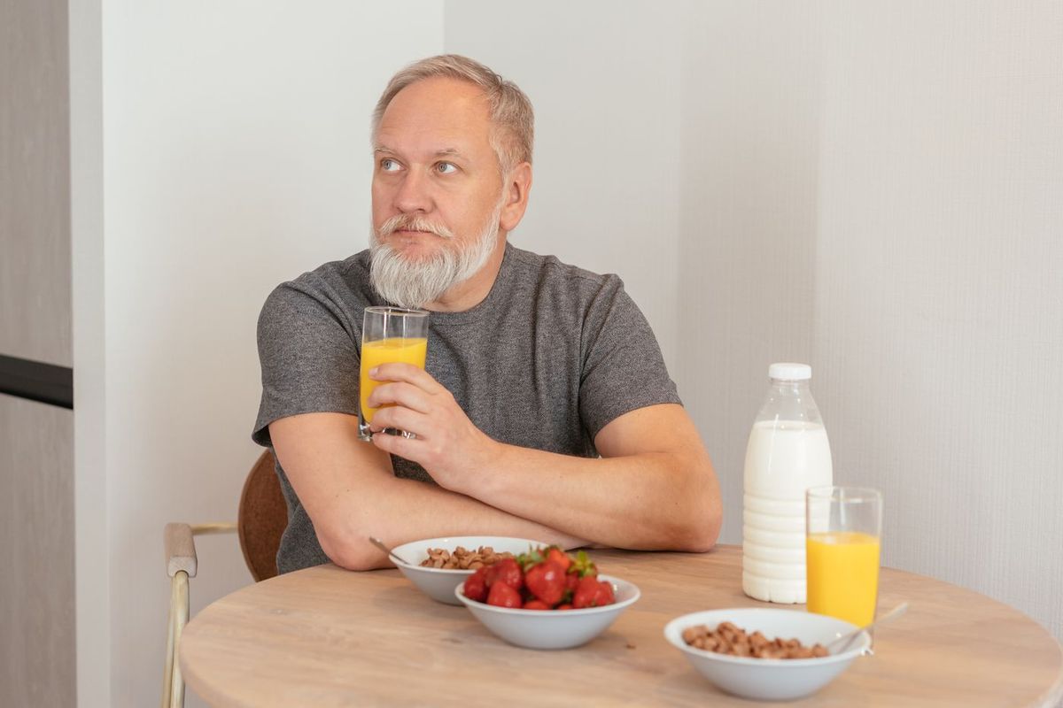 Homme à la table de la cuisine avec un verre et un petit-déjeuner