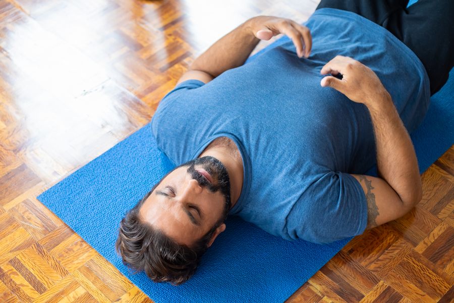 Homme allongé sur le dos sur un tapis bleu